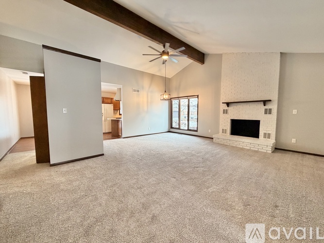 A spacious living room with a fireplace and a ceiling fan.