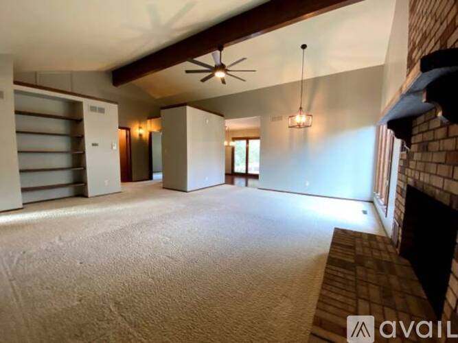 A spacious room with a ceiling fan and a fireplace.