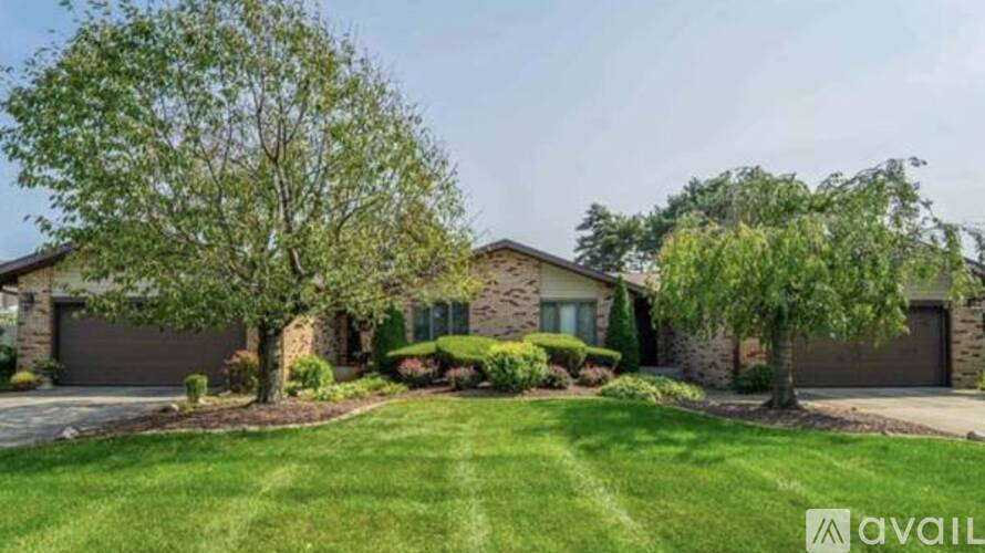 A house with a well-maintained lawn and trees in front.