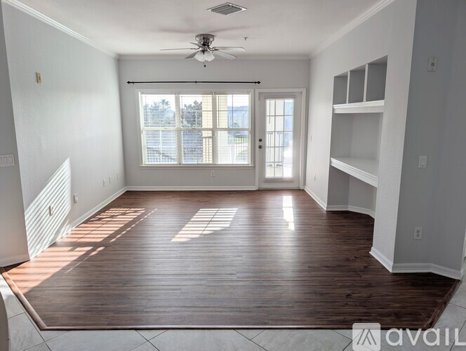 A spacious room with wooden flooring and a ceiling fan.