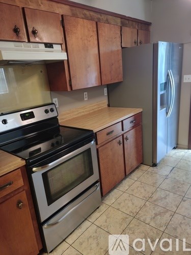 A kitchen with wooden cabinets and a stainless steel refrigerator.