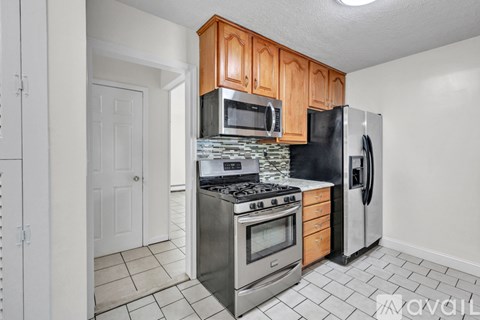 A kitchen with wooden cabinets and a black refrigerator.
