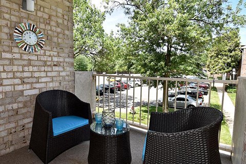a balcony with two chairs and a table and a clock on the wall
