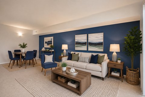 A living room with a white couch, blue chairs, and a painting on the wall.