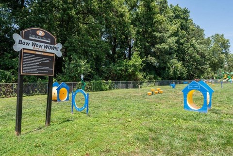 a park with a sign and playground equipment in the grass
