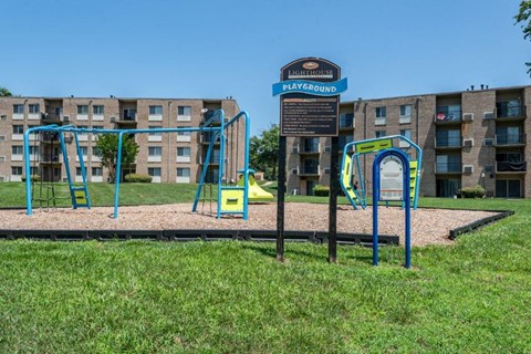 a playground with a sign in front of an apartment building