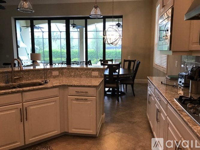 A kitchen with white cabinets and a large island with a sink.