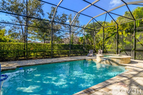 A pool inside a glass house with a brick walkway.