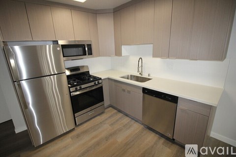 A kitchen with a stainless steel refrigerator, microwave, oven, and sink.