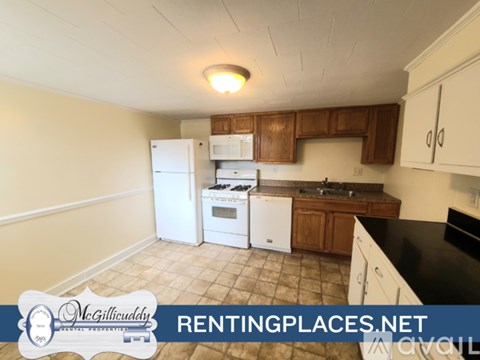 A kitchen with white appliances and wooden cabinets.