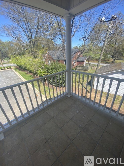 A balcony with a metal railing and a view of a parking lot and trees.