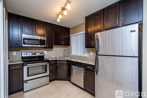 A kitchen with dark brown cabinets and stainless steel appliances.