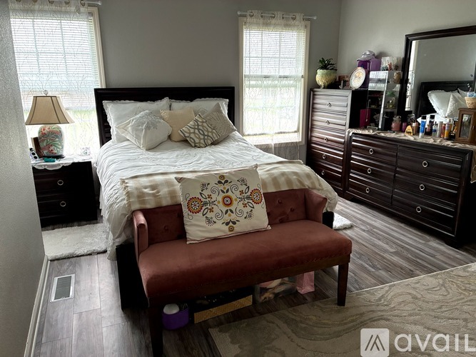 A bedroom with a bed, a bench, and a dresser.