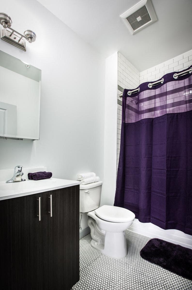 bathroom with white tile shower, modern wooden cabinet, and white walls