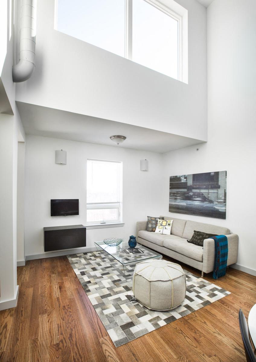 Living Room with beige couch, glass coffee table and neutral patterned rug