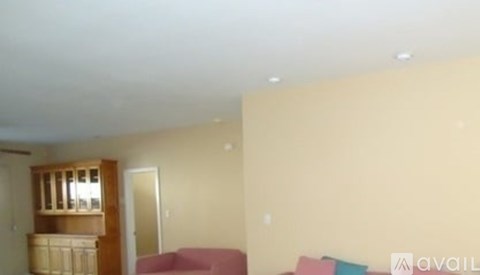 A living room with a pink couch and a wooden cabinet.