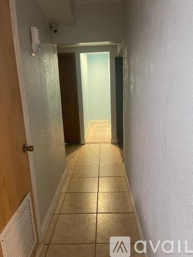 A hallway with a tiled floor and a door at the end.