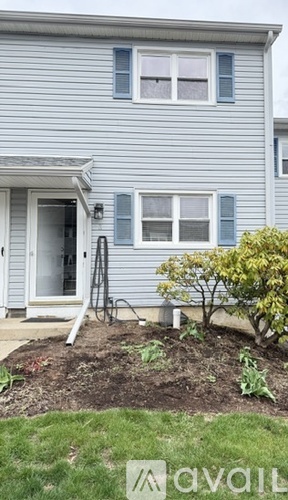 A house with a grey siding and a small garden in front.