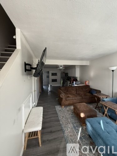 A living room with a couch, chair, ottoman, and television.
