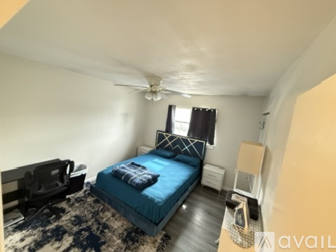 A bedroom with a bed, a chair, and a ceiling fan.