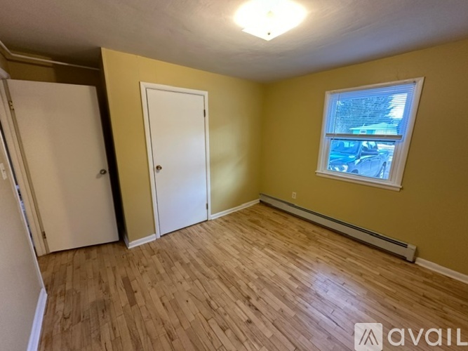A room with wooden flooring and a window with blinds.