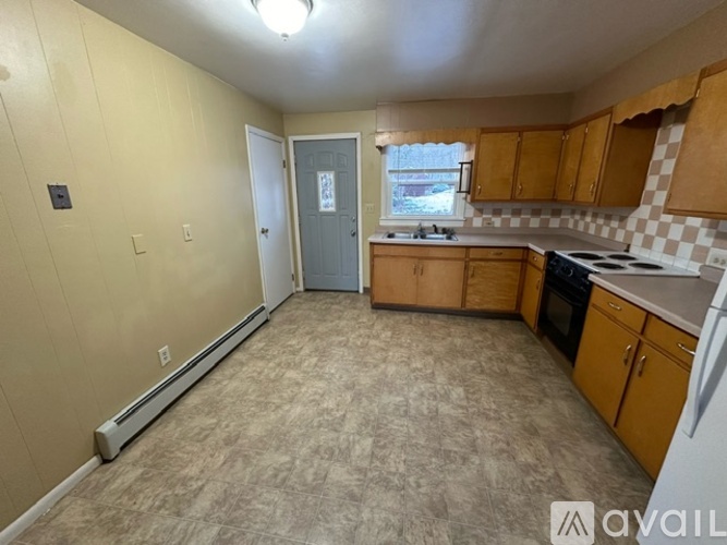 A kitchen with a white refrigerator, wooden cabinets, and a tile floor.