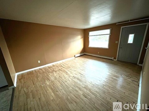 A room with wooden flooring and a window letting in natural light.