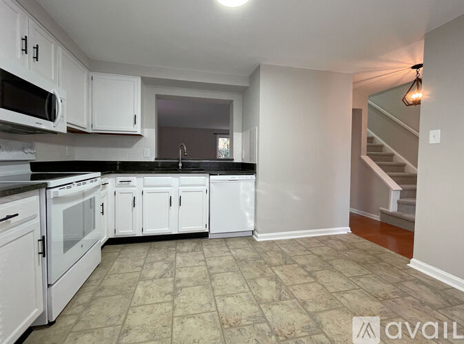 A kitchen with white cabinets and black countertops.