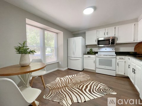 A kitchen with white cabinets and black countertops.