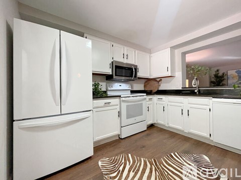 A kitchen with white appliances and cabinets.
