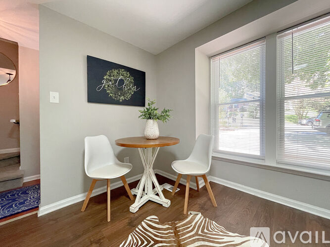 A spacious room with a carpeted floor and white walls, with a door to the right and a window to the left.