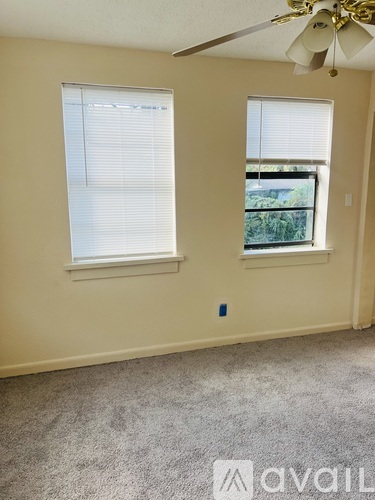 A room with two windows and a ceiling fan.