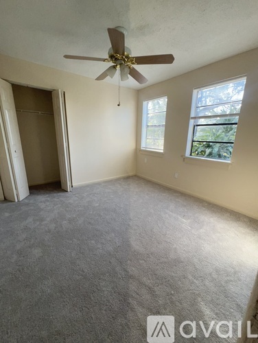 A room with a ceiling fan and carpeted floor.