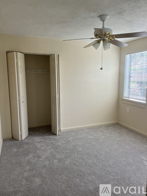 A room with a ceiling fan and a window with blinds.