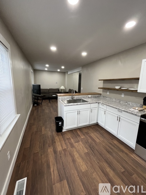 A kitchen with white cabinets and a wooden floor.