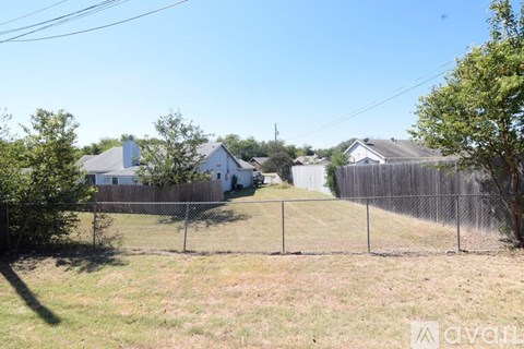A backyard with a fence and a house in the background.