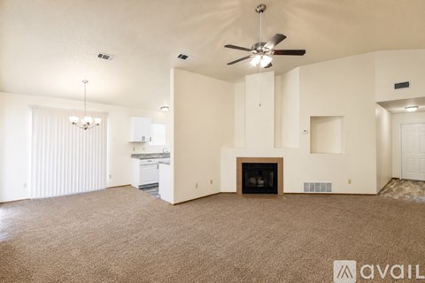 A spacious living room with a fireplace and a ceiling fan.