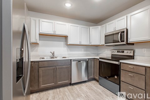 A kitchen with white cabinets and a stainless steel refrigerator.