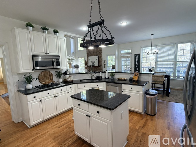 A kitchen with white cabinets and black countertops.