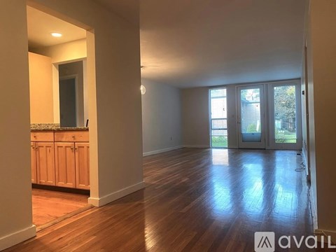 A room with wooden floors and a kitchen area with cabinets and a countertop.