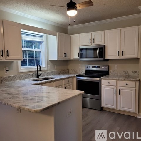 A kitchen with white cabinets and a marble countertop.