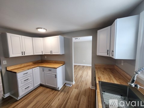 A kitchen with white cabinets and a wooden island.