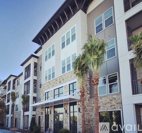 A modern apartment building with palm trees in front.