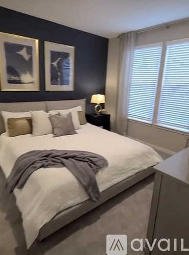 A bedroom with a white bed and a grey blanket.