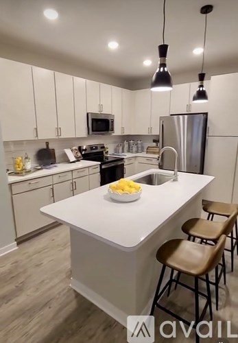 A kitchen with white cabinets and a white island with brown chairs.