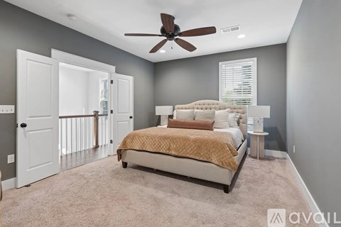 A bedroom with a bed, carpet, and a ceiling fan.