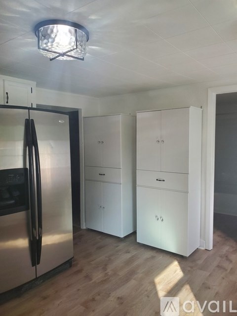 A kitchen with a stainless steel refrigerator and white cabinets.