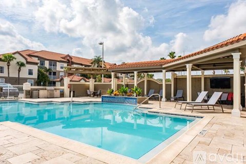 A pool area with a clear blue pool and sun loungers.