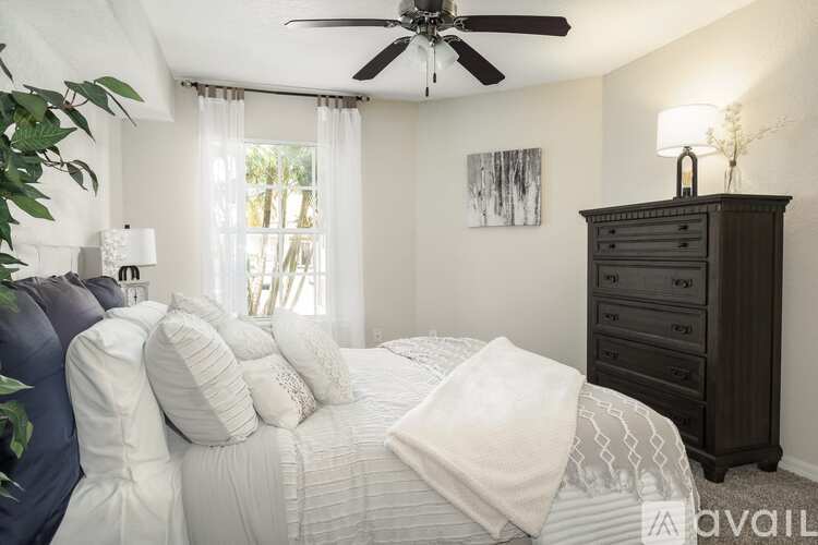 A bedroom with a large bed, a ceiling fan, and a dresser.