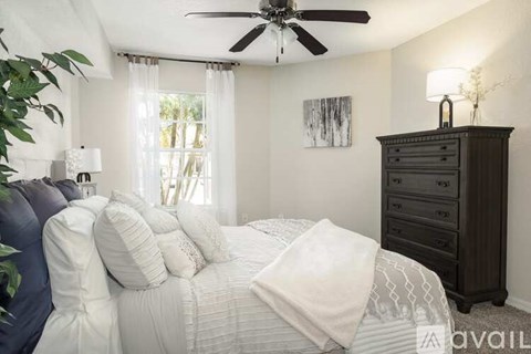 A bedroom with a large bed, a ceiling fan, and a dresser.
